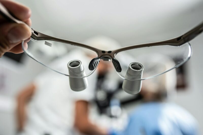 Close-up of dental loupes with blurred background, depicting a dentist at work.