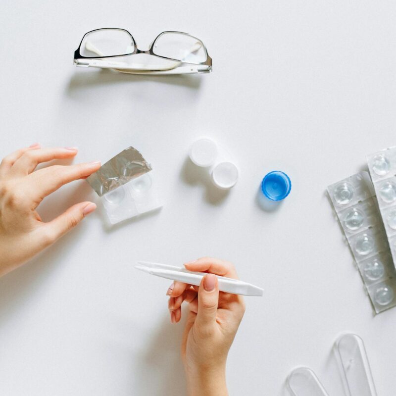Flat lay setup of contact lenses with eyeglasses for eye care on a white background.